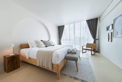 a white bedroom with a bed and a large window at The STYLISH Hometel Sukhumvit in Bangkok