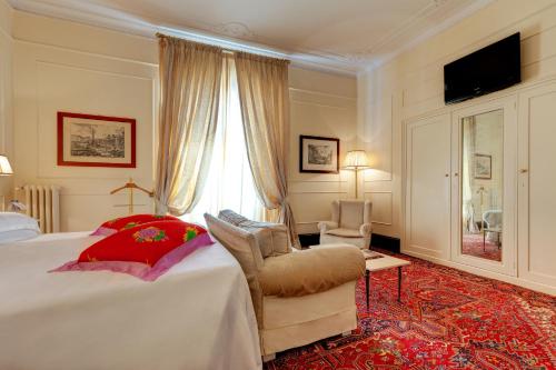 a bedroom with a bed and a chair and a window at Grand Hotel Plaza in Rome