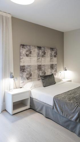 a bedroom with a large white bed with a headboard at Apartamentos Real Lleida in Lleida