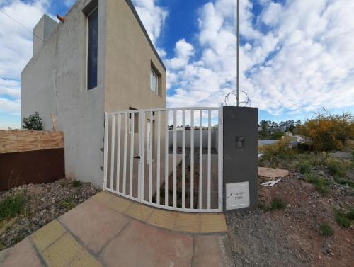 una puerta frente a una casa con una valla en Dúplex con patio y parrilla en Terrazas del Sol en Neuquén