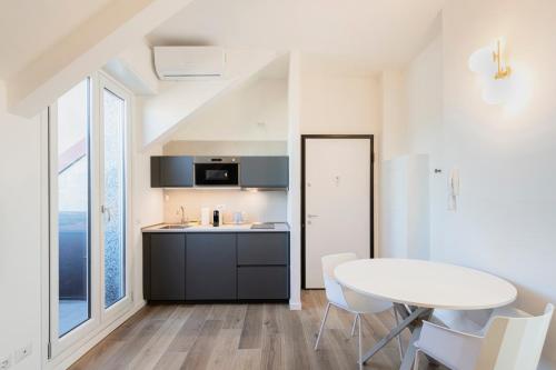 eine Küche mit einem weißen Tisch, einem Tisch und Stühlen in der Unterkunft RELSTAY - Tortona in Mailand