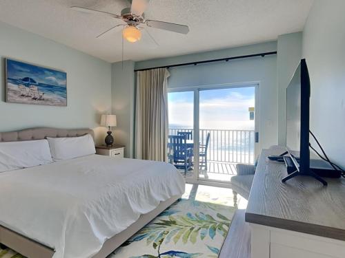 a bedroom with a bed and a television and a balcony at Tidewater Orange Beach #1003 in Orange Beach