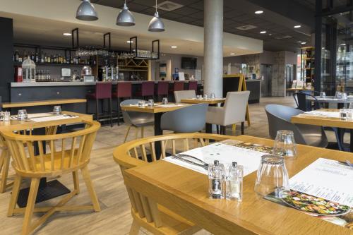 a restaurant with wooden tables and chairs and a bar at Campanile Le Mans Centre - Gare in Le Mans