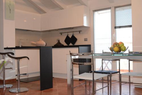 a kitchen with white cabinets and a counter with chairs at Casa Marcone in Deiva Marina