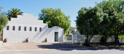 un bâtiment blanc avec une porte verte et un arbre dans l'établissement Aloe Cottage, à Montagu