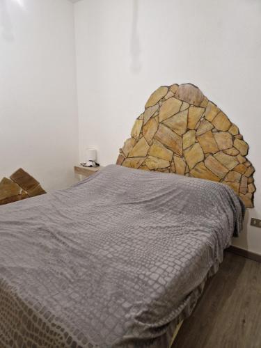 1 dormitorio con 1 cama con cabecero de piedra en Appartamento isola rossa vista mare, en Isola Rossa