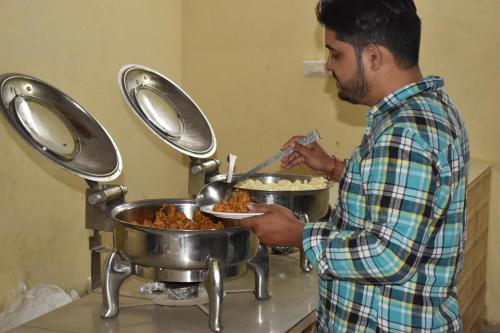Ein Mann bereitet Essen in zwei Töpfen vor. in der Unterkunft Mumal Desert Camp - Jaisalmer ! in Sām