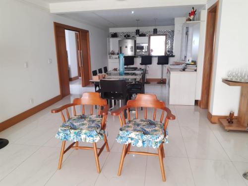 a living room with three chairs and a kitchen at RICARDO Pousada Q1 Suíte in Vila Velha