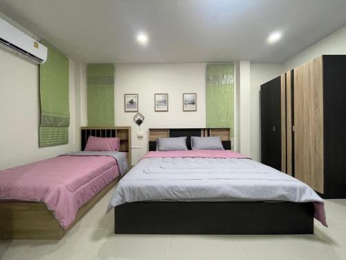 2 letti in una camera da letto con pareti verdi e bianche di อีโฮสเทลบ้านช่น a Ban Chak Khamin
