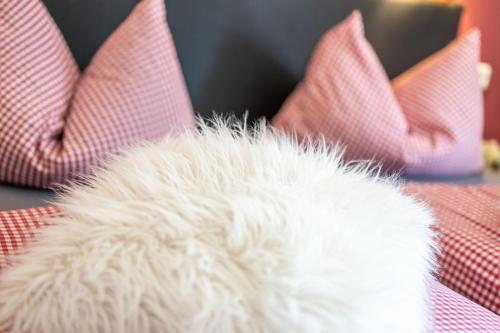 a white furry object sitting on a table with red pillows at Ferienwohnung Alpensonne in Oberstdorf