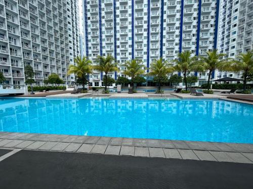 a large blue swimming pool in front of tall buildings at Rich Staycation Makati in Manila