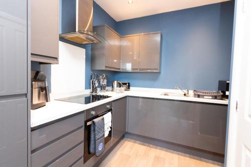 cocina con electrodomésticos de acero inoxidable y paredes azules en Modern Stylish 1Bed Apartment in Birkenhead, en Birkenhead