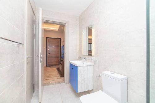 a white bathroom with a toilet and a sink at Spacious 1-Bed Apt at Elite (7D) in Nairobi