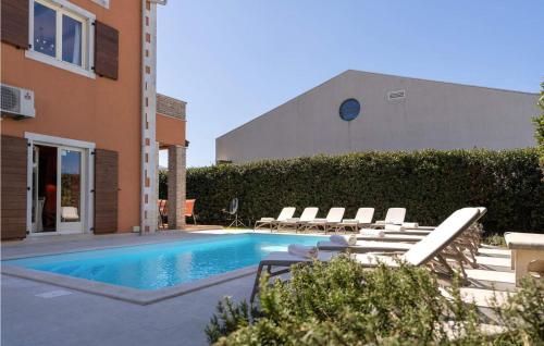 una piscina con sedie a sdraio accanto a un edificio di Villa Leon a Funtana