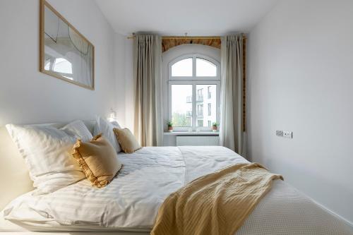 a white bed in a bedroom with a window at Fabryczna 19 by Farkas Apartments in Poznań
