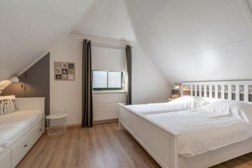 a white bedroom with a bed and a window at Buitenplaats 27 Callantsoog in Callantsoog