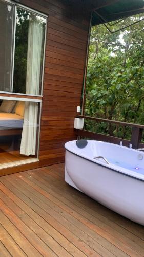 a bath tub sitting on a deck next to a window at Chalé Verde Prána in Brumadinho