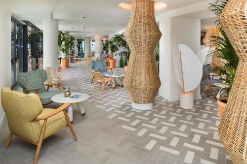 a lobby with chairs and tables and vases at ME Sitges Terramar in Sitges