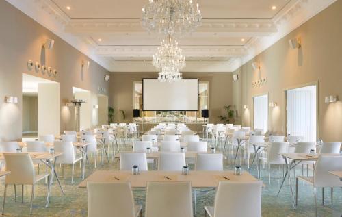 a room with tables and white chairs and a projection screen at ME Sitges Terramar in Sitges