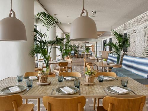 a restaurant with tables and chairs and plants at ME Sitges Terramar in Sitges