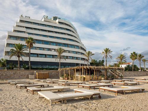 a building on the beach with a bunch of benches at ME Sitges Terramar in Sitges