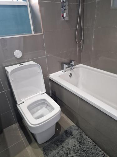 a bathroom with a toilet and a bath tub at Stylish and Unique Bedroom In Gateshead - Close To Newcastle in Sheriff Hill