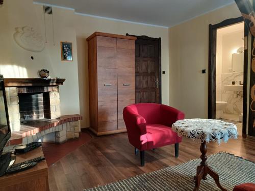uma sala de estar com uma cadeira vermelha e uma mesa em Pensjonat Wiking em Stare Jabłonki