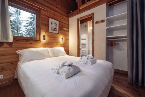 a bedroom with a large white bed with towels on it at Madame Vacances Chalet Morgane in La Tania