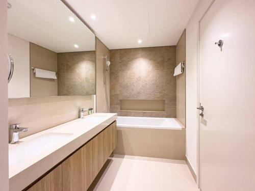 a bathroom with two sinks and a bath tub at Downtown Views 2BR Luxury Apartment Pool and City Skyline in Dubai