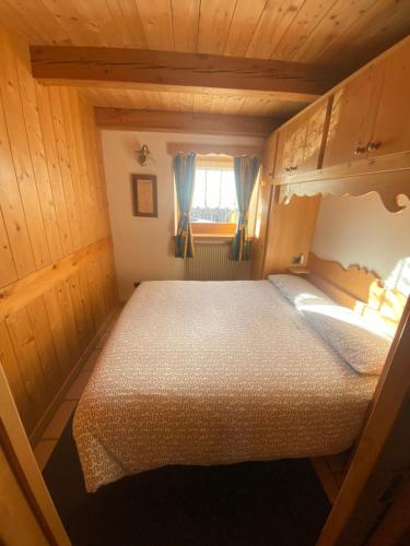 1 dormitorio con 1 cama en una cabaña de madera en Appartamento al Tabià Pizal, en Santo Stefano di Cadore