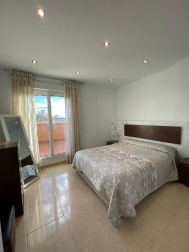 a bedroom with a large bed and a large window at Ático Peñíscola in Peñíscola