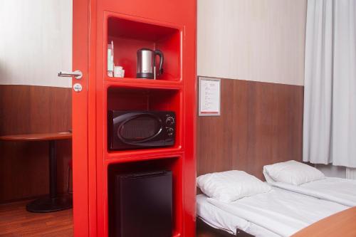 a red book shelf with a microwave and a bed at Omena Hotel Helsinki City Centre in Helsinki
