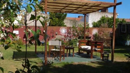 Casa en Necochea في نيكوتشيا: بريغولا خشبي في حديقة مع طاولة وكراسي