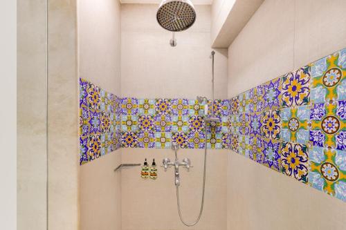 a bathroom with a shower with colorful tiles on the wall at Lemon Tree Amarante Beach Resort, Goa in Candolim