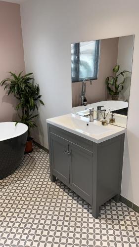 a bathroom with a sink and a tub and a mirror at Modern Harrogate house sleeps 10, cinema room & hot tub in Harrogate