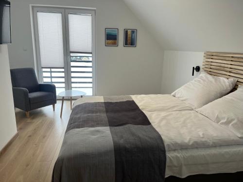 a bedroom with a bed and a chair and a window at Domek nad stawem in Krynica Zdrój