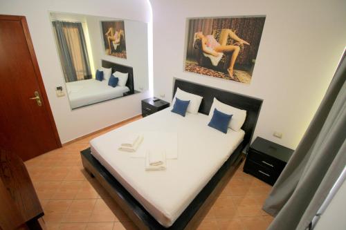 a bedroom with a large bed with white sheets and blue pillows at Oskar Hotel in Sarandë