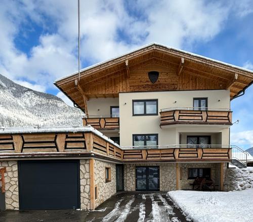 a house in the snow with a garage at Ferienwohnungen LODGE-B in Weissenbach am Lech