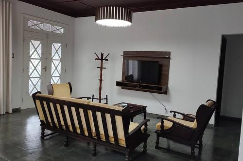 excelente casa ótima localização في أوباتوبا: غرفة معيشة مع مقعد وكراسي وتلفزيون
