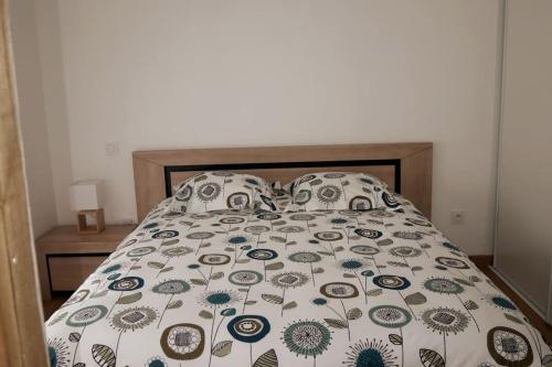 ein Bett mit geblümter Bettdecke und Kissen in der Unterkunft Appartement T2, avec Terrasse. in La Roche-sur-Yon