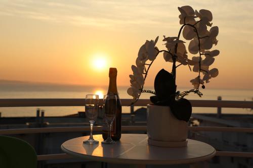 a table with two glasses and a bottle of wine and a plant at Oskar Hotel in Sarandë
