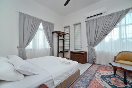a bedroom with a bed and a chair and windows at Villapadu Kota in Kuala Terengganu