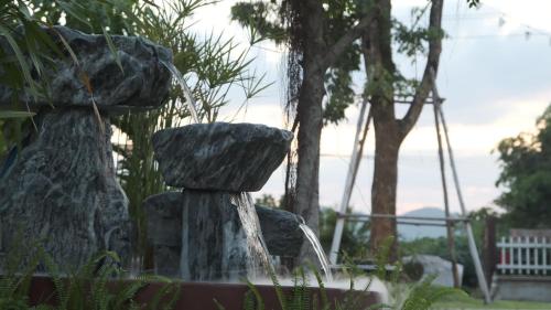 a water fountain with two rocks in a park at Namas Kan Farmstay in Kanchanaburi
