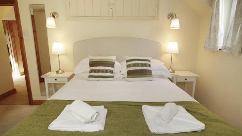 a bedroom with a white bed with towels on it at Bull Croft Cottage in Oxwich