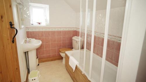 a bathroom with a tub and a toilet and a sink at Bull Croft Cottage in Oxwich