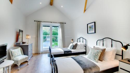 a bedroom with two beds and a desk and a tv at Roman Bridge Close in Oystermouth