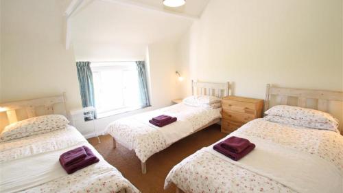 - une chambre avec 3 lits et une fenêtre dans l'établissement Middleton Hall Cottage, à Rhossili