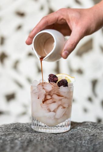 a person pouring a drink from a cup at Mala Garden Design Hotel in Siófok