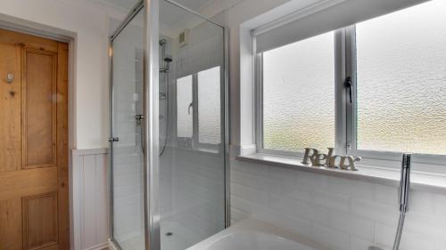 a bathroom with a shower and a sink and a window at Misgrove House Annexe in Newton
