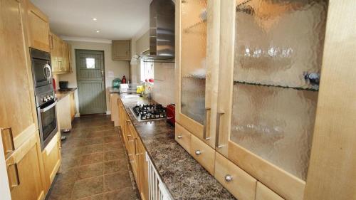 a kitchen with wooden cabinets and a stove top oven at Woodside in Parkmill